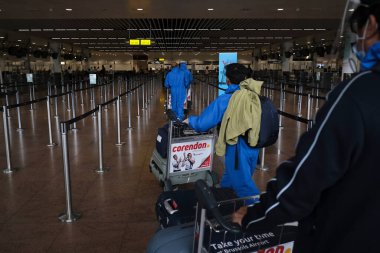 Koronavirüsün yayılmasını önlemek için maske takan yolcular, 24 Temmuz 2020 'de Brüksel, Belçika' daki Zaventem uluslararası havaalanındaki panoya bakın.