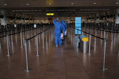 Koronavirüsün yayılmasını önlemek için maske takan yolcular, 24 Temmuz 2020 'de Brüksel, Belçika' daki Zaventem uluslararası havaalanındaki panoya bakın.