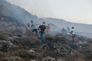 İtfaiyeciler ve gönüllüler 12 Ağustos 2020 'de Yunanistan' ın Santorini adasındaki Kamari köyünde çıkan yangını söndürmeye çalışıyorlar.