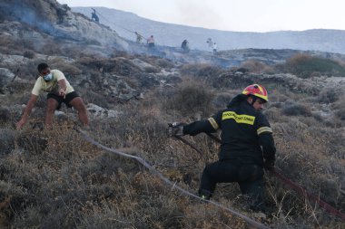 İtfaiyeciler ve gönüllüler 12 Ağustos 2020 'de Yunanistan' ın Santorini adasındaki Kamari köyünde çıkan yangını söndürmeye çalışıyorlar.