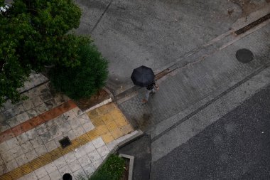 Atina, Yunanistan 'da 7 Ağustos 2020' de sağanak yağış sırasında şemsiyeli bir yaya sokakta yürüyor