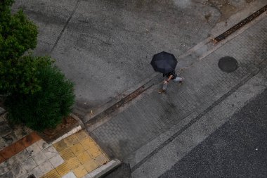 Atina, Yunanistan 'da 7 Ağustos 2020' de sağanak yağış sırasında şemsiyeli bir yaya sokakta yürüyor