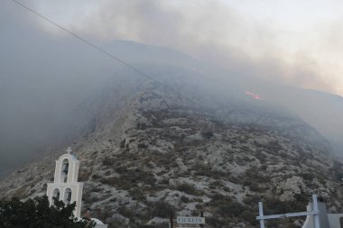 12 Ağustos 2020 'de Yunanistan' ın Santorini adasındaki Kamari köyü yakınlarında yanan ateşten duman yükseliyor