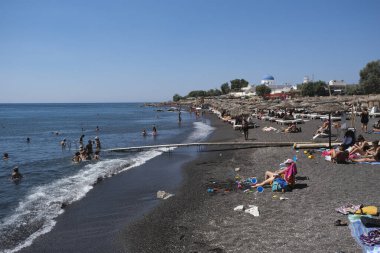 İnsanlar 13 Ağustos 2020 'de Yunanistan' ın Santorini kentinde Perissa plajında güneşli bir gün ve denizin keyfini çıkarıyorlar..