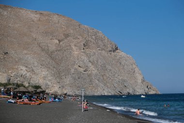 İnsanlar 13 Ağustos 2020 'de Yunanistan' ın Santorini kentinde Perissa plajında güneşli bir gün ve denizin keyfini çıkarıyorlar..