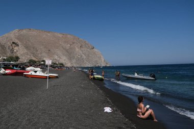 İnsanlar 13 Ağustos 2020 'de Yunanistan' ın Santorini kentinde Perissa plajında güneşli bir gün ve denizin keyfini çıkarıyorlar..