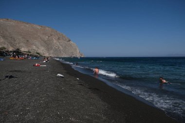 İnsanlar 13 Ağustos 2020 'de Yunanistan' ın Santorini kentinde Perissa plajında güneşli bir gün ve denizin keyfini çıkarıyorlar..