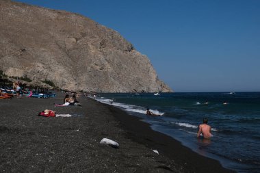 İnsanlar 13 Ağustos 2020 'de Yunanistan' ın Santorini kentinde Perissa plajında güneşli bir gün ve denizin keyfini çıkarıyorlar..