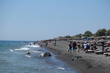 İnsanlar 13 Ağustos 2020 'de Yunanistan' ın Santorini kentinde Perissa plajında güneşli bir gün ve denizin keyfini çıkarıyorlar..
