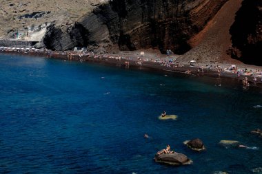 İnsanlar 14 Ağustos 2020 'de Yunanistan' ın Santorini adasındaki Kızıl Sahilde yüzerken güneşli havanın tadını çıkarıyorlar.