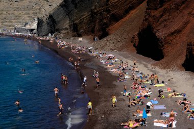 İnsanlar 14 Ağustos 2020 'de Yunanistan' ın Santorini adasındaki Kızıl Sahilde yüzerken güneşli havanın tadını çıkarıyorlar.