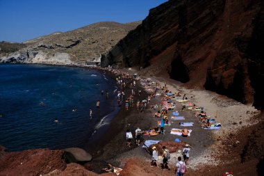 İnsanlar 14 Ağustos 2020 'de Yunanistan' ın Santorini adasındaki Kızıl Sahilde yüzerken güneşli havanın tadını çıkarıyorlar.