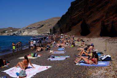 İnsanlar 14 Ağustos 2020 'de Yunanistan' ın Santorini adasındaki Kızıl Sahilde yüzerken güneşli havanın tadını çıkarıyorlar.
