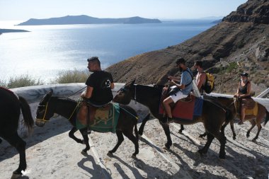 15 Ağustos 2020 'de Yunanistan' ın Fira kentinin limanına giden merdiven, kaldera manzaralı eşek ve atların üzerindeki turistler