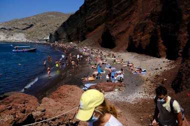 İnsanlar 14 Ağustos 2020 'de Yunanistan' ın Santorini adasındaki Kızıl Sahilde yüzerken güneşli havanın tadını çıkarıyorlar.