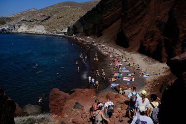 İnsanlar 14 Ağustos 2020 'de Yunanistan' ın Santorini adasındaki Kızıl Sahilde yüzerken güneşli havanın tadını çıkarıyorlar.