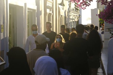 Koruyucu maske takan insanlar, 17 Ağustos 2020 'de Yunanistan' ın Oia kentindeki pitoresk bir köyde yürürler..
