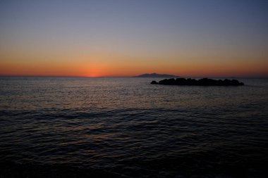 Sahilde denizden doğan güneşin görüntüsü