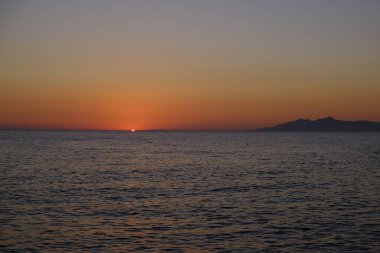 Sahilde denizden doğan güneşin görüntüsü