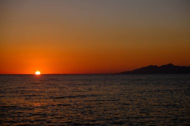 Sahilde denizden doğan güneşin görüntüsü