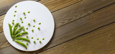 Ahşap bir arka plan üzerinde bir taş tahta üzerinde lezzetli, yeşil, taze bezelye.