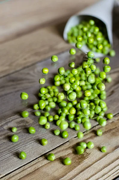Tasty, green, fresh peas in a paper bag on a wooden background.
