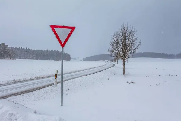 Vita tomma snöiga iskalla vintern vägen spåra med lämna företräde-skylt — Stockfoto
