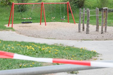 Corona virüsü karantina altına alınması çocuk parkı salınımlarını yasaklıyor. Bariyer bandıyla kapatma. Covid-19, salgın riski içeren güvenlik önleme eylemi. Kanun yönetmelikleriyle Coronavirus kısıtlaması