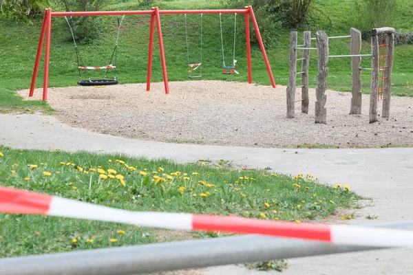 Corona virus quarantine lockdown prohibit playground swings. Closure by barrier tape. Covid-19 safety prevention action containing pandemic spread risk. Coronavirus restriction by law regulations