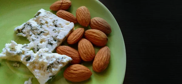 Blue cheese with almond nuts on green plate