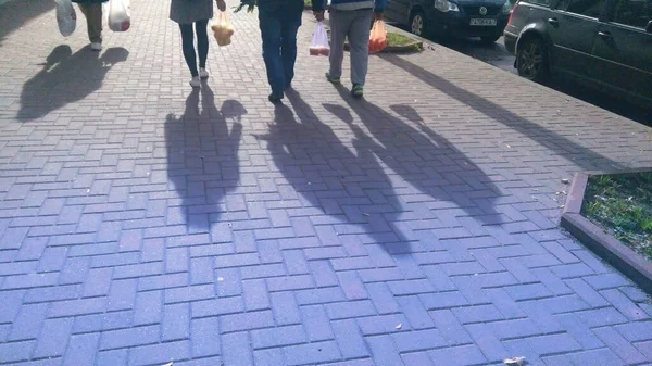 People with plastic bags and their shadows in the street — Stock Photo, Image