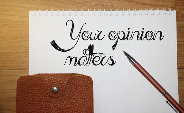 Text phrase Your opinion matters on page, a pen and wallet on wooden table. Education and business development concept.