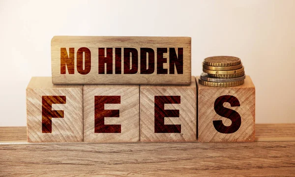 No hidden fees word written on wood blocks and pill of coins. Business agreement transparency and honesty concept.
