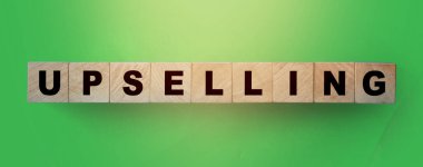 Yeşil eğimli arka planda tahta küplerle ilgili kelime UPSELING. İş konsepti.