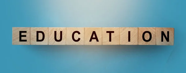 Istruzione Parola scritta in cubi di legno in sfondo sfumato blu. Competenze e concetto di apprendimento — Foto Stock