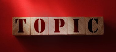 Kırmızı arkaplanda tahta bloklu TOPIC kavramı.