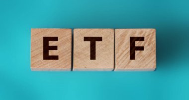 ETF, Exchange Traded Fund, hisse senedi piyasasında ticaret yapabilen gerçek zamanlı yatırım fonu, Aquamarine mavi kağıt üzerinde ETF kelimesinin alfabe oluşturulduğu küp tahta blok.