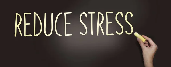Reduce Stress Written in yellow chalk on a blackboard. No stress and relax mental health healthcare concept.