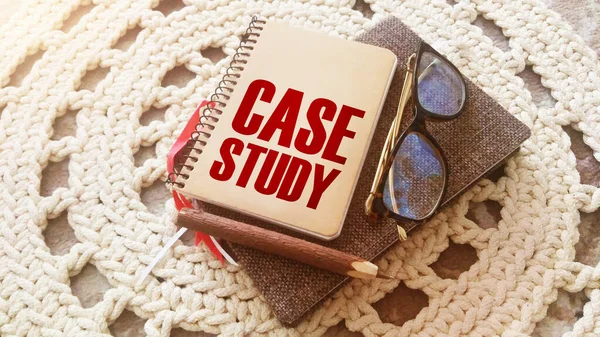 Case study memo written on a notebook with pen, glasses on crochet cloth. Successful business cases educational concept