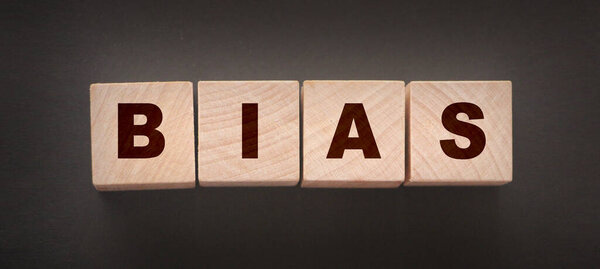 Слово "BIAS" пишется деревянными буквенными плитками на черном фоне..