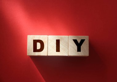 Ahşap küp bloklar ve kırmızı arka planda DIY harfleri. Kopyalama alanı ile iş kavramı