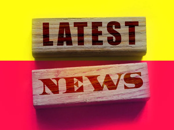 Latest News words on a wooden blocks on yellow and magenta background. Fake or real facts concept. Mass media breaking news concept