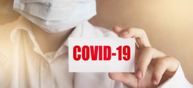 Doktor elinde COVID-19 yazılı bir kart tutuyor. Tıbbi sağlık konsepti..