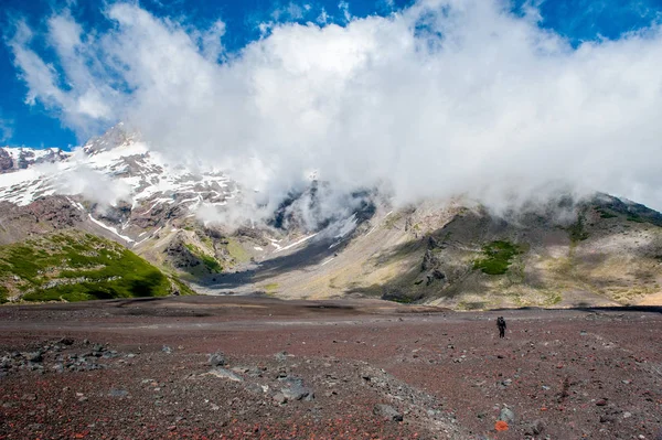 A young woman with backpack hiking on iceberg and snow and enjoying the views of the Antuco volcano black volcano desert. Northern Patagonia, Andes, Chile, South America.