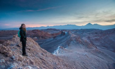 Genç kadın tek başına Valle de la Luna Moon Vadisi'nde gün doğumunu izliyor, San Pedro de Atacama Şili. Dünyaca ünlü Atacama çöl Şili kum oluşumu üzerinde çarpıcı güneş doğuşu geniş bir görünüm. Tuz oluşumları 
