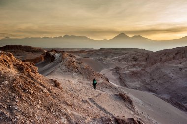 Genç kadın tek başına Valle de la Luna Moon Vadisi'nde gün doğumunu izliyor, San Pedro de Atacama Şili. Dünyaca ünlü Atacama çöl Şili kum oluşumu üzerinde çarpıcı güneş doğuşu geniş bir görünüm. Tuz oluşumları 