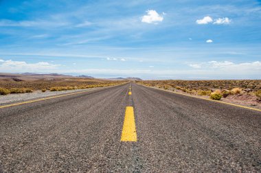 Arka planda dağlar ve bulutlar ile düşük açıdan Amerikan boş çöl asfalt yol. Atacama çölünde Güney Amerika otoyolu, Şili. Sarı çizgili yol.