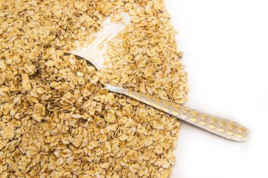 Beyaz arka plana saçılmış metal bir kaşıkta yulaf ezmesi. Beslenme yemeği. Sağlıklı kahvaltı. Doku ve arka plan..