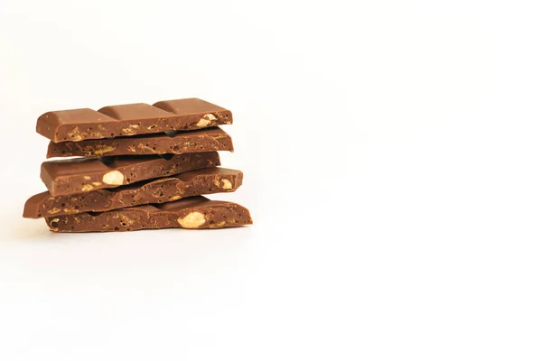 Fatias de chocolate são empilhadas em um fundo branco.Chocolate escuro com nozes . — Fotografia de Stock