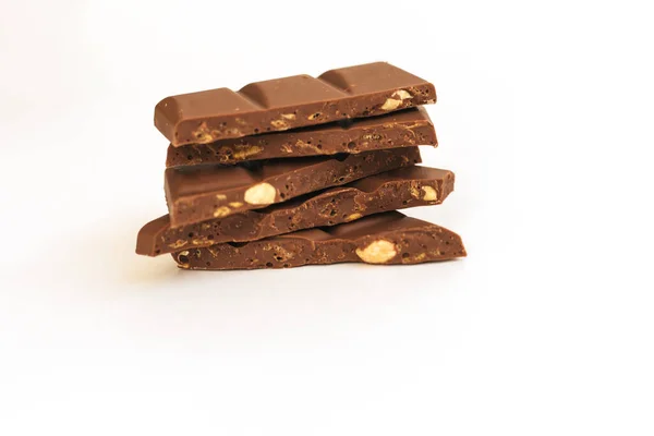 Fatias de chocolate são empilhadas em um fundo branco.Chocolate escuro com nozes . — Fotografia de Stock